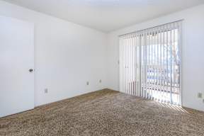 A room with a carpeted floor and a window with blinds.