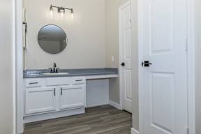 A bathroom with a sink, mirror, and lighting fixture.