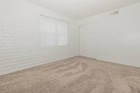 A room with a carpeted floor and a window with blinds.