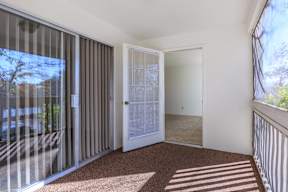 A room with a carpet floor, a white door, and a balcony with a railing.