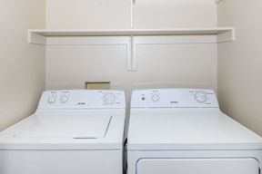 Two white front loading washing machines in a laundry room.