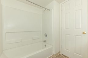 A white bathroom with a tub and a door.