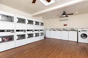 A laundry room with a row of washers and dryers.