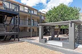 A modern building with a balcony and a tree in the background.
