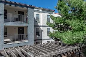A modern apartment building with a balcony and a tree in front.