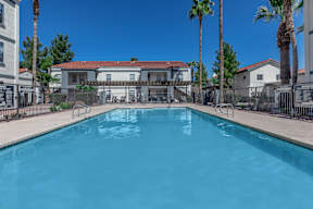 A swimming pool surrounded by palm trees and a fence.