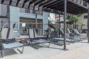 A row of sun loungers are on a patio.