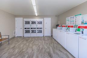 A room with white cabinets and a wall of fridges.