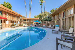 A pool surrounded by chairs and umbrellas.