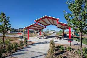 A red and white canopy structure is situated in a park-like setting.