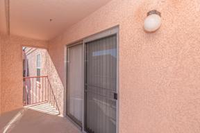 A balcony with a glass door and a red railing.