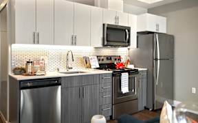 A modern kitchen with stainless steel appliances and a tiled backsplash.