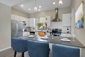 A modern kitchen with a large island and blue chairs.
