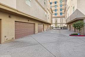 A long, narrow driveway between two buildings with garage doors.