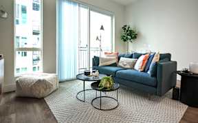 A living room with a blue couch and a glass table.