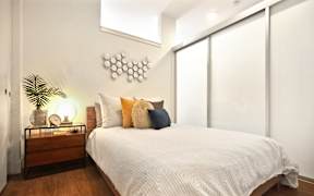 A bedroom with a bed, nightstand, and a wall hanging.