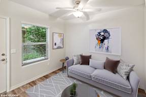 A living room with a grey couch and a painting on the wall.