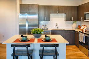 A kitchen with a white island and two chairs.