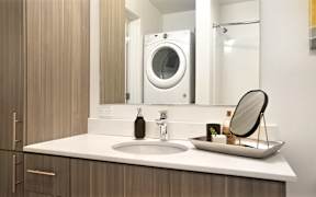 A modern bathroom with a sink, mirror, and a washing machine.