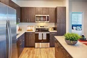 A modern kitchen with wooden cabinets and stainless steel appliances.