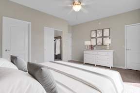 A white bedroom with a bed, dresser, and mirror.