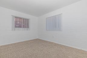 A room with a carpeted floor and two windows.