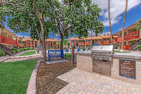 A BBQ grill is in the middle of a landscaped courtyard.