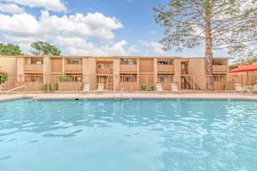 A swimming pool in front of a building with a tree in the background.