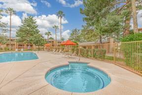 A pool surrounded by a fence with trees in the background.