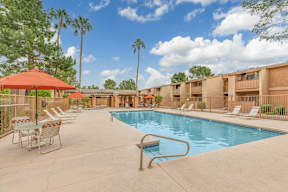 A pool surrounded by chairs and umbrellas in a sunny day.