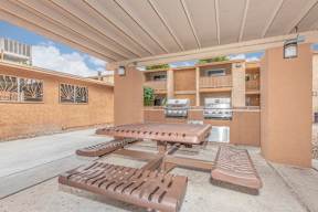 Picnic tables and benches are set up under a covered patio.