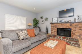 A grey couch with orange pillows and a fireplace in a living room.