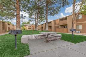 A courtyard with a picnic table surrounded by trees and buildings.