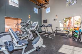 A gym with treadmills, elliptical machines, and a fan.