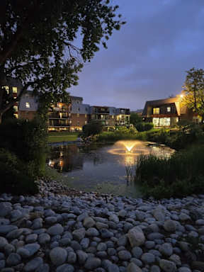 A serene evening view of a pond with a building in the background.