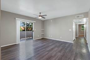 A room with a ceiling fan and sliding glass doors.