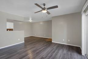 A room with a ceiling fan and wooden flooring.