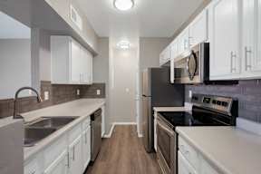 A kitchen with white cabinets and a black refrigerator.