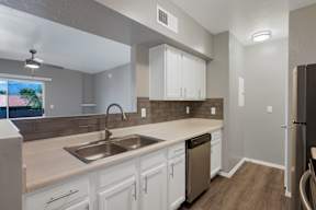 A kitchen with white cabinets and a stainless steel sink.