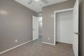A room with a ceiling fan and two doors.