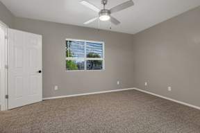 A room with a ceiling fan and a window with blinds.