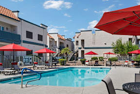 A pool surrounded by red umbrellas and chairs.