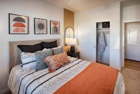 A bedroom with a bed, pillows, and artwork on the wall.