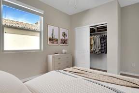 A bedroom with a large bed, a dresser, and a window with a view of a roof.
