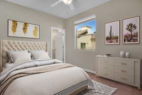 A bedroom with a large bed, a ceiling fan, and a window showing a house outside.