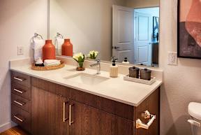 A bathroom with a white counter top and wooden cabinets.