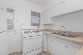 A white kitchen with a sink and a stove.
