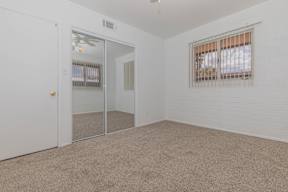 A room with a carpeted floor, a window with blinds, and a sliding glass door.
