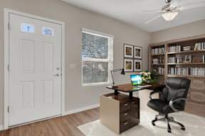 A home office with a desk, chair, and bookshelf.
