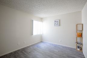 A room with a wooden floor and a picture frame on the wall.